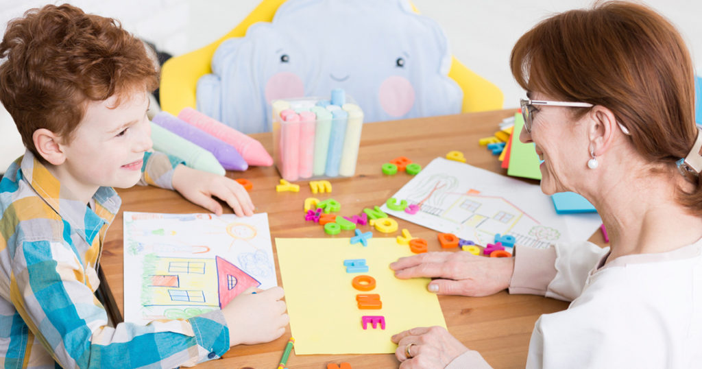 woman and child at table with alphabet blocks and construction paper