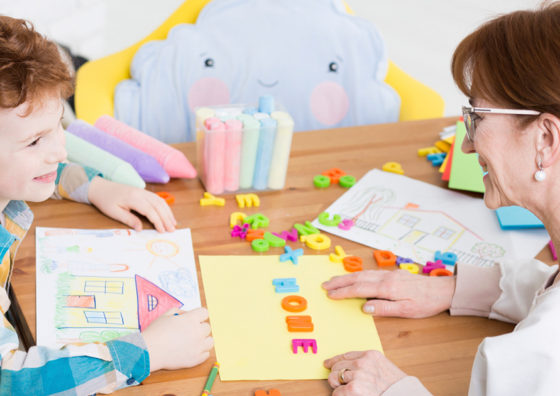 woman and child at table with alphabet blocks and construction paper