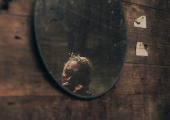 old man's face reflected in mirror
