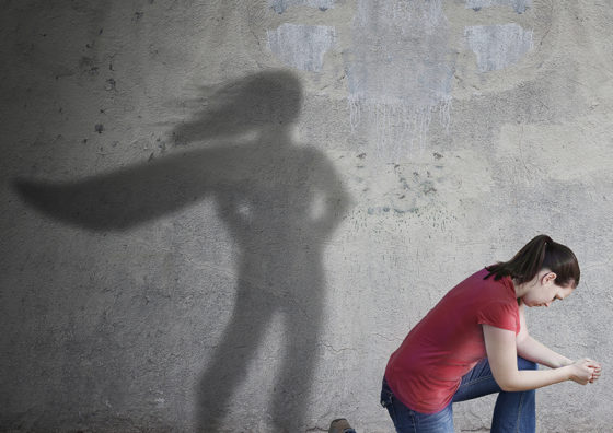 person kneeling in front of shadow with cape