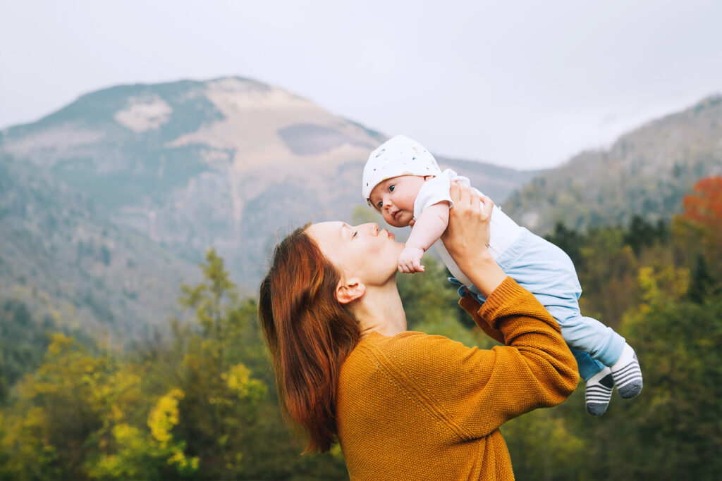 A mother holds up her baby and kisses his face