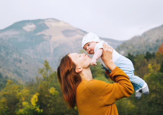 A mother holds up her baby and kisses his face